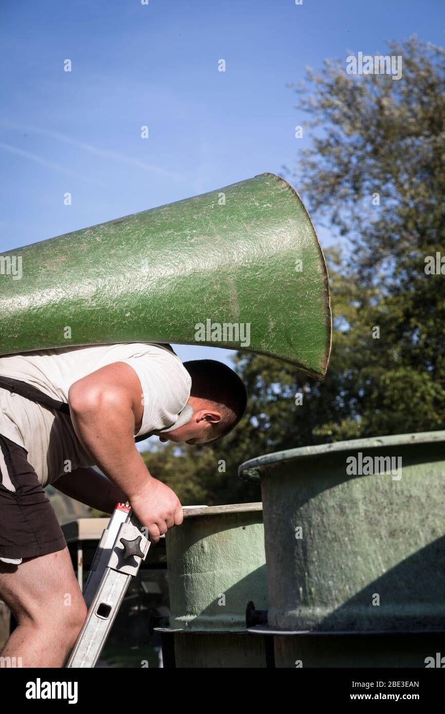 Man tips grapes from his backpack collector into a large collecting bin during the grape harvest in Piesport, Germany. Stock Photo