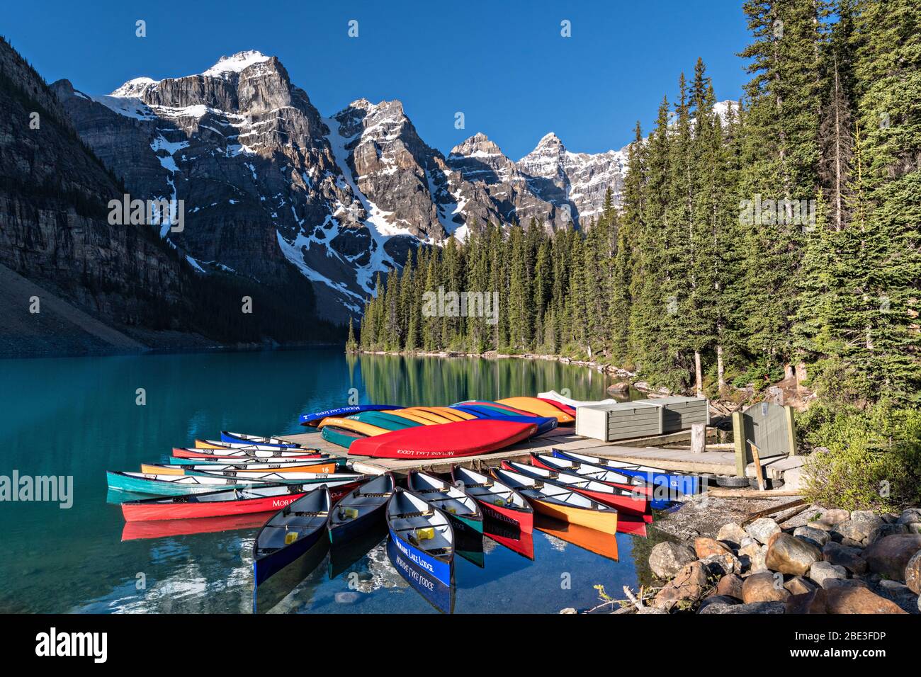 Colorful canoes docked in the turquoise waters of Lake Louise and the snow dusted Fairview Mountain behind in Banff National Park in Alberta, Canada. Stock Photo