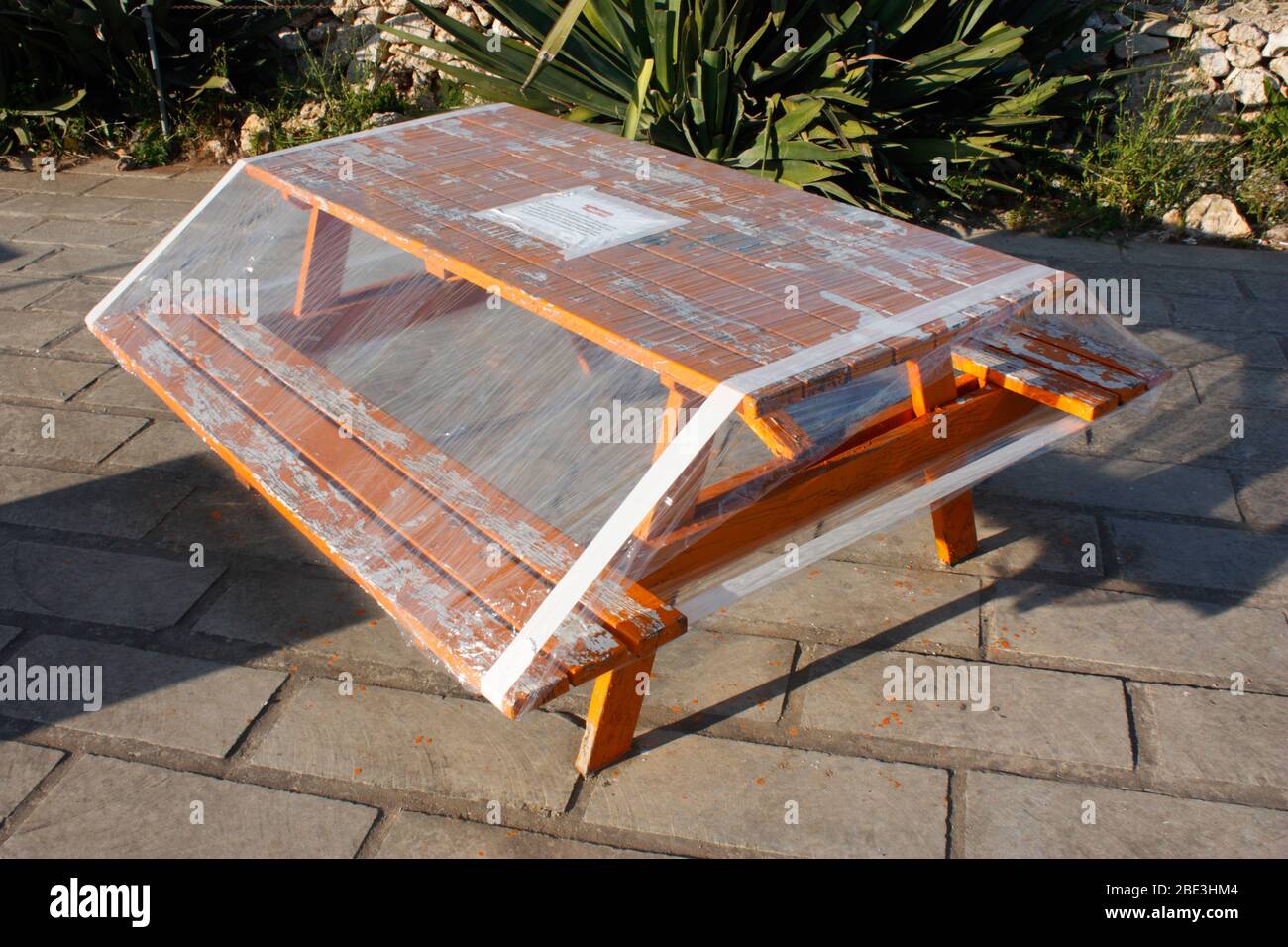 Picnic table covered in plastic film to enforce lockdown during the Covid-19 coronavirus pandemic in Europe Stock Photo