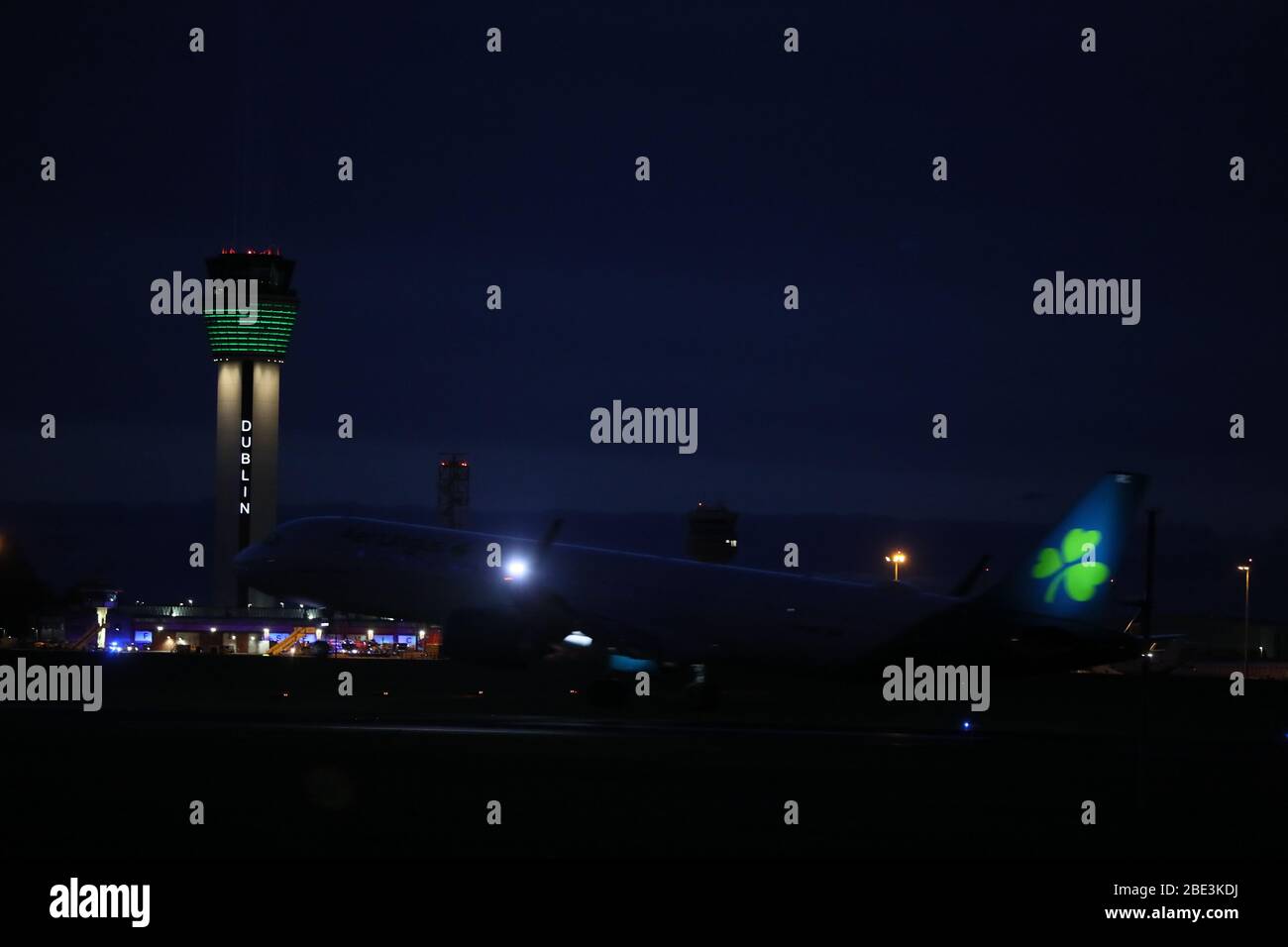An Aer Lingus flight lands at Dublin Airport as a large beam of light shines out of the new air traffic control tower as part of the Shine Your Light campaign in tribute to front line health workers and those affected by the coronavirus outbreak. Stock Photo