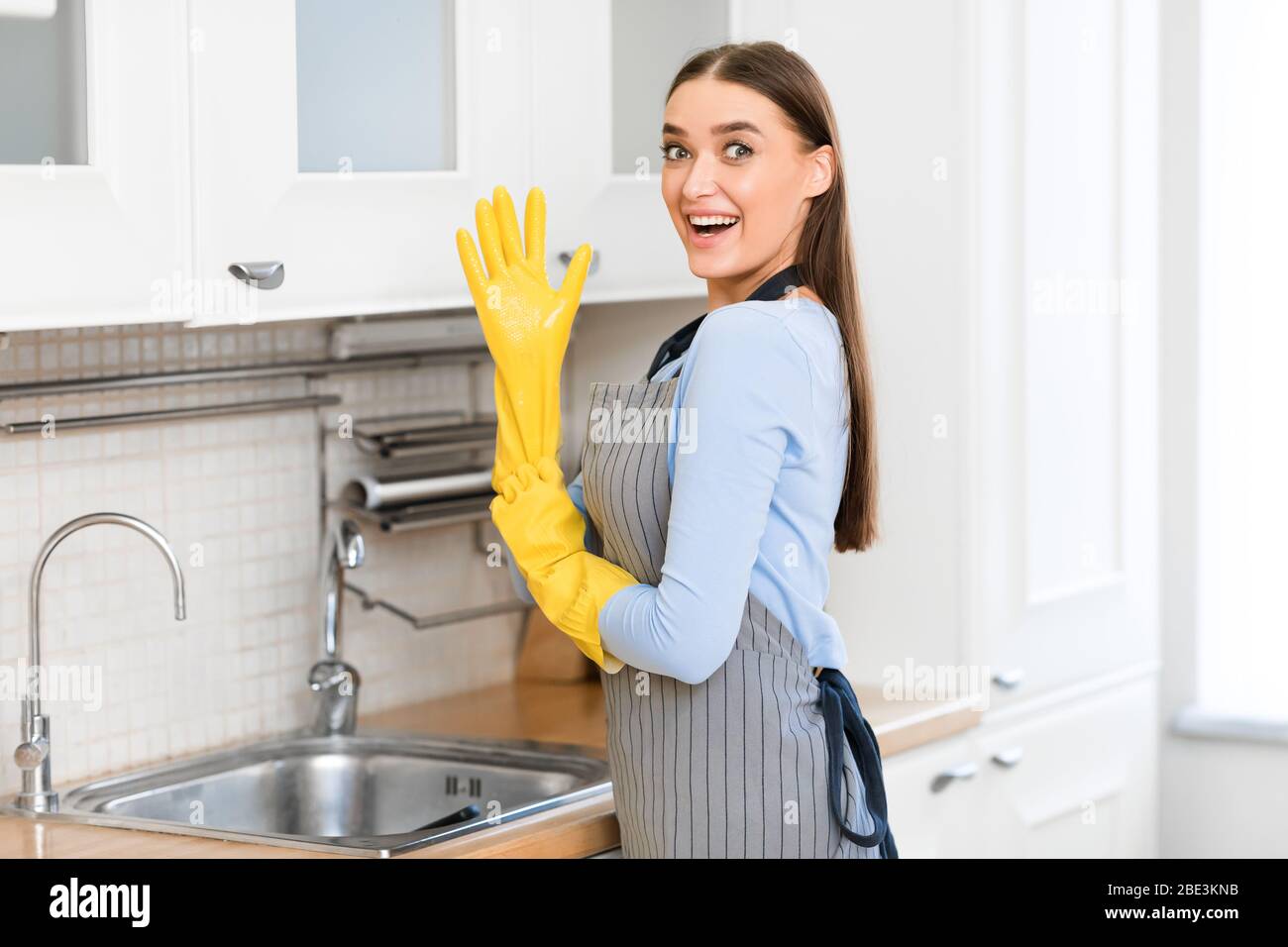 Funny woman putting on yellow rubber gloves Stock Photo Alamy