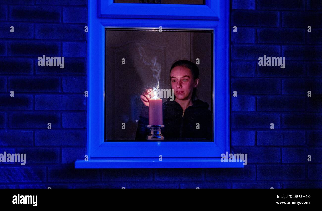 Maisy Byrne lights a candle in the window of a home in Liverpool after the Queen stressed the importance of maintaining the coronavirus lockdown during the Easter Bank Holiday weekend as she delivered what is believed to be her first Easter address. Stock Photo