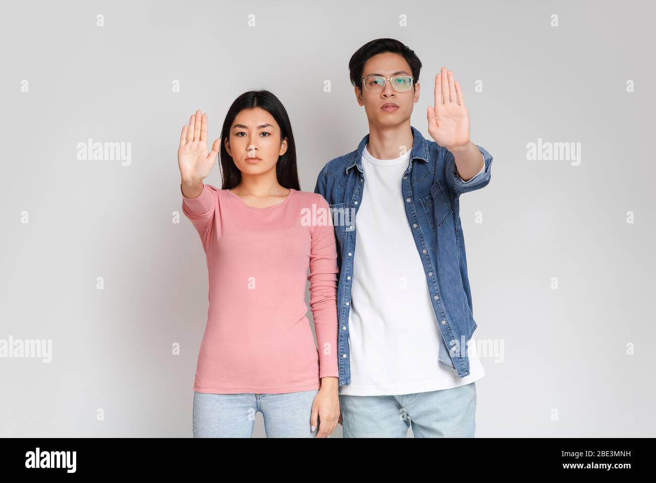 Young asian couple standing over grey background, doing stop sign Stock Photo