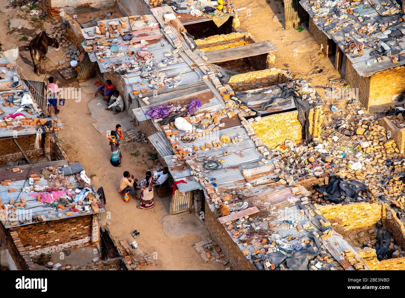 Aerial dusk shot of people sitting outside their broken brick and tin ...