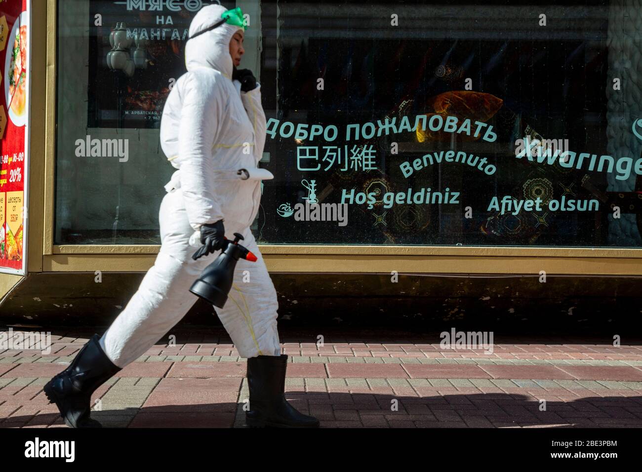 Moscow, Russia.11th April, 2020. A worker in special clothing make disinfection on Arbat street in Moscow during the novel coronavirus COVID-19 pandemic in Russia. A worker walks against the background of a showcase with inscriptions in different languages reading 'Welcome' Stock Photo