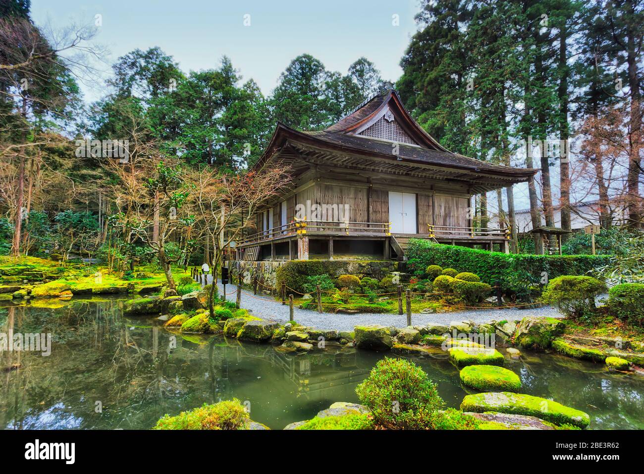 Still pond with stone steps across to remote traditional japanese building in japanese garden near Kyoto. Stock Photo