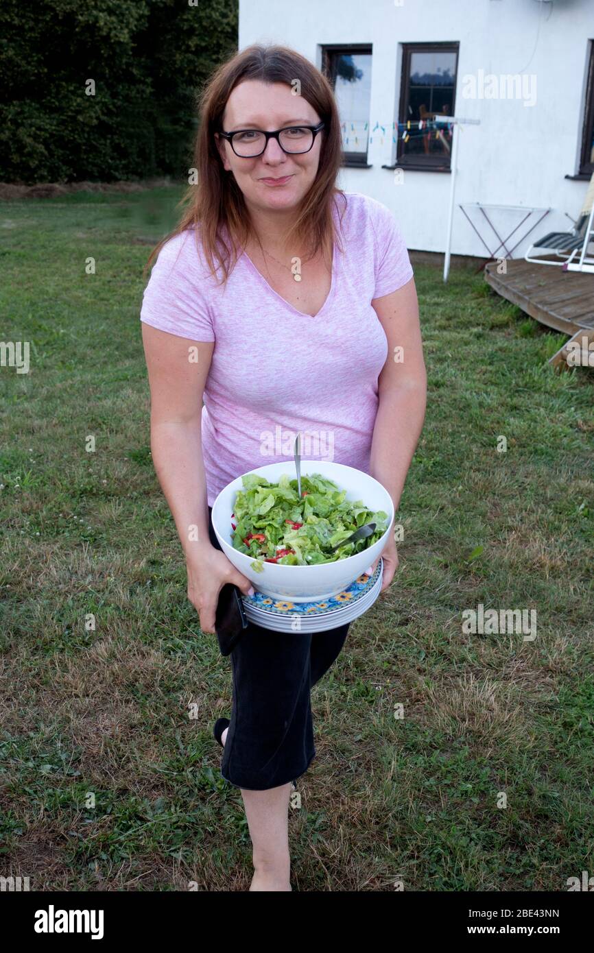 Polish woman holding bowl of fresh green salad for a family outdoor barbecue in her yard. Zawady Gmina Rzeczyca Poland Stock Photo