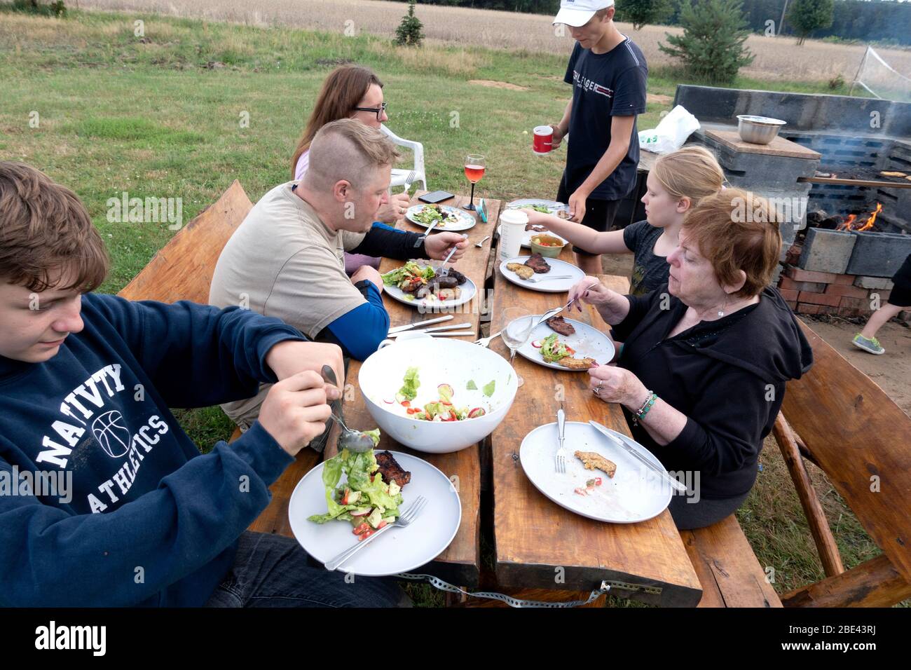 Polish family of three generations enjoying a meal at the picnic table in their yard. Zawady Gmina Rzeczyca Poland Stock Photo