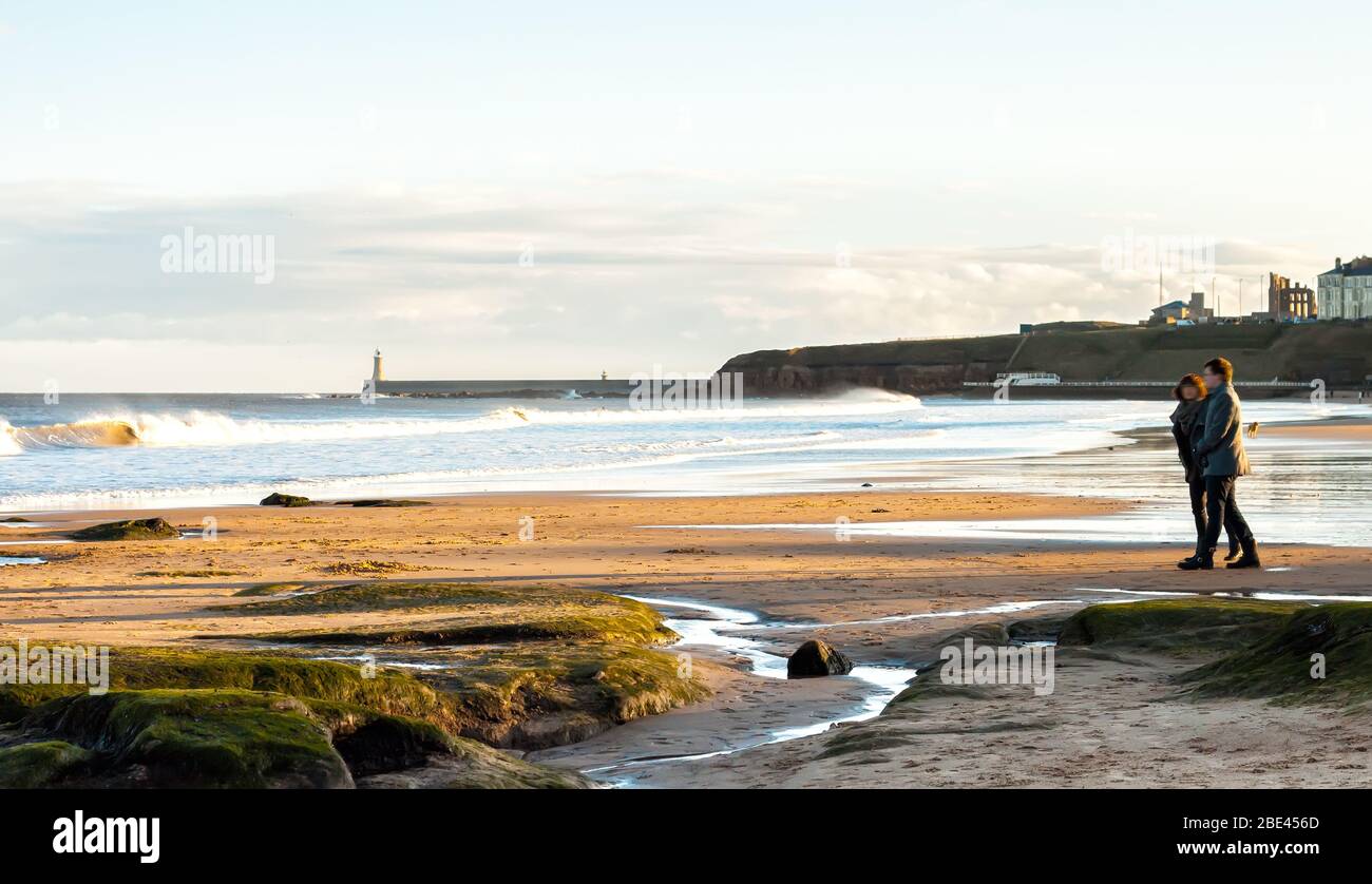Panoramic View of Couple walking on the British Seaside at Sunset in Tynemouth, United Kingdom Stock Photo
