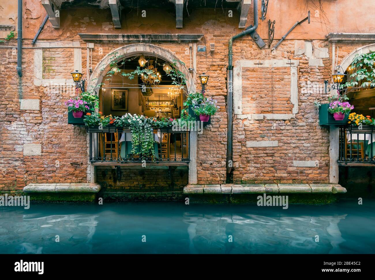 Traditional Italian Restaurant with Warm Lighting along Scenic Venetian Canal in Venice, Italy Stock Photo