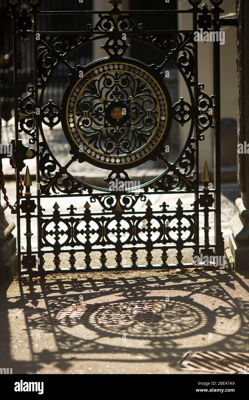 A wrought iron Victorian gate casts an ornate shadow at the entrance to Highgate Cemetery on Swain's Lane in London, England, United Kingdom. Stock Photo
