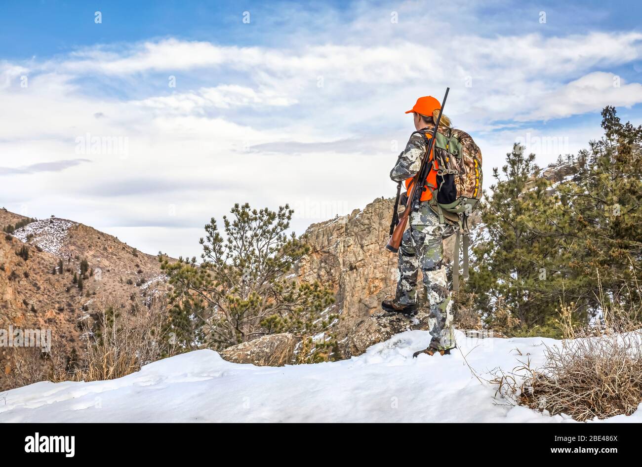 Hunter with camouflage clothing and rifle looking out in winter; Denver, Colorado, United States of America Stock Photo