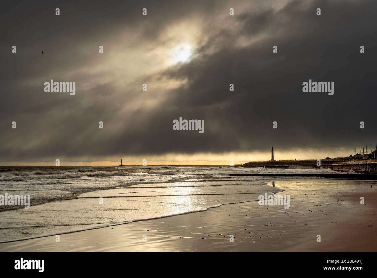Silhouetted lighthouses along the coastline under dramatic cloudy sky; Whitburn Village, Tyne and Wear, England Stock Photo