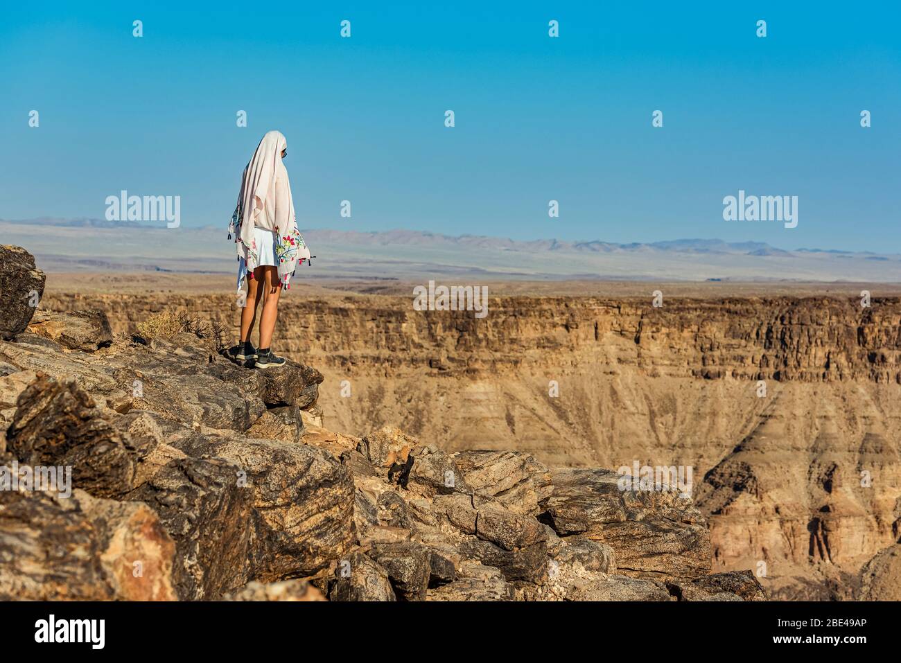 Female tourist stands looking out over Fish River Canyon; Namibia Stock Photo