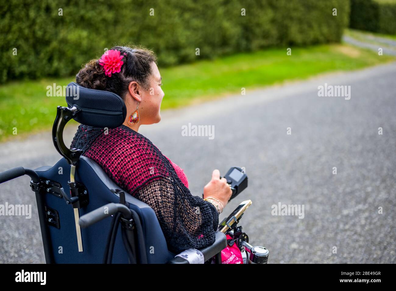 Maori woman with Cerebral Palsy in a wheelchair going down a sidewalk;  Wellington, New Zealand Stock Photo - Alamy
