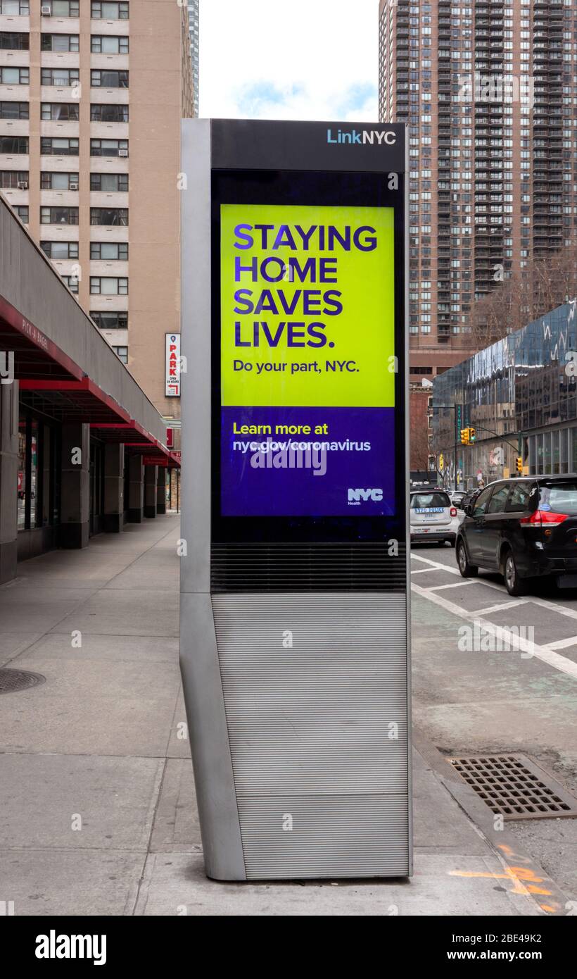a public service announcement on a digital street sign by the nyc government says staying home saves lives during the coronavirus or covid-19 pandemic Stock Photo