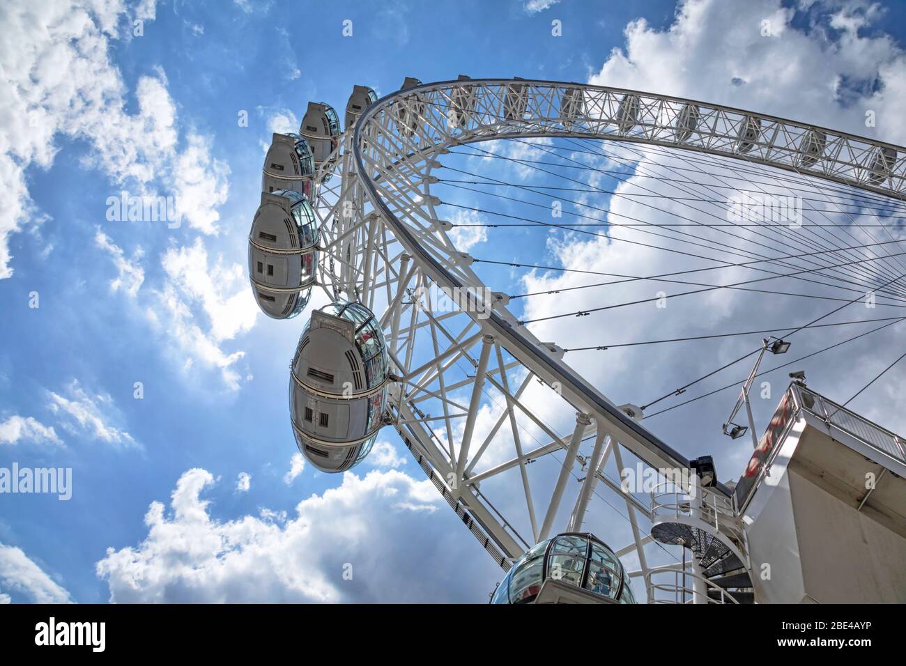 View from directly below the cables and pods of the London Eye with a blue sky and clouds in the background; London, England Stock Photo