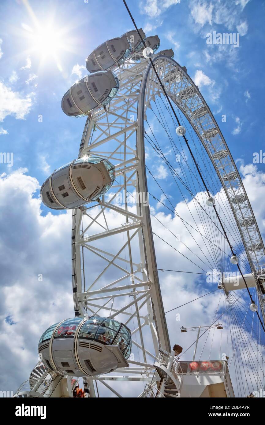 View from directly below the cables and pods of the London Eye with a blue sky and clouds in the background; London, England Stock Photo
