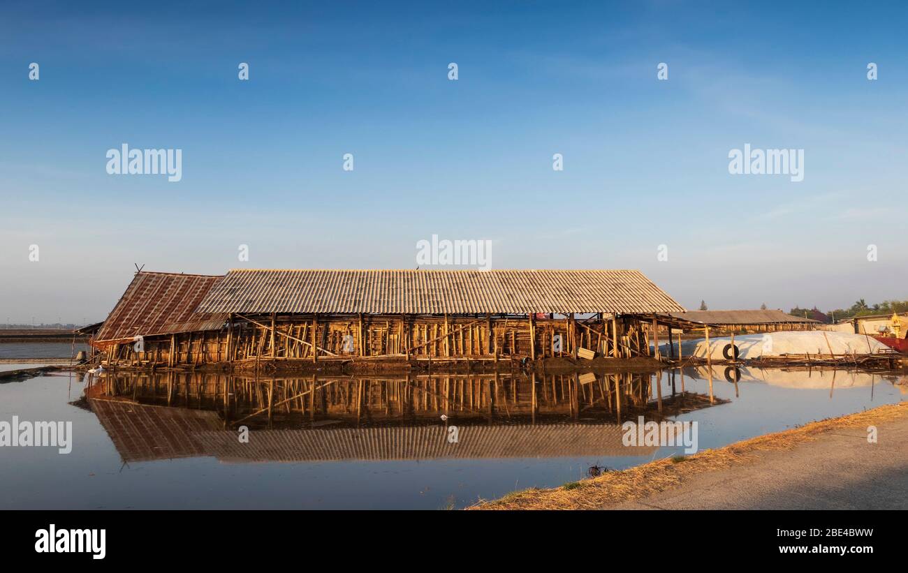 Salt is produced by the evaporation of seawater; then harvested by the salt farmers and stored in traditional buildings at Pak Thale. Stock Photo