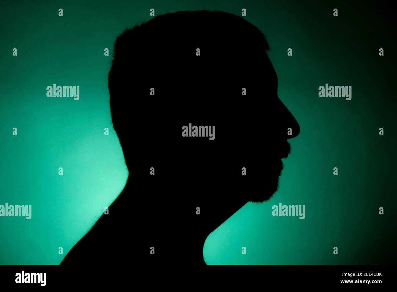 Cleanly defined silhouette of a male person turned to the left against a  green background with a spotlight and bright area right behind the bust  Stock Photo - Alamy