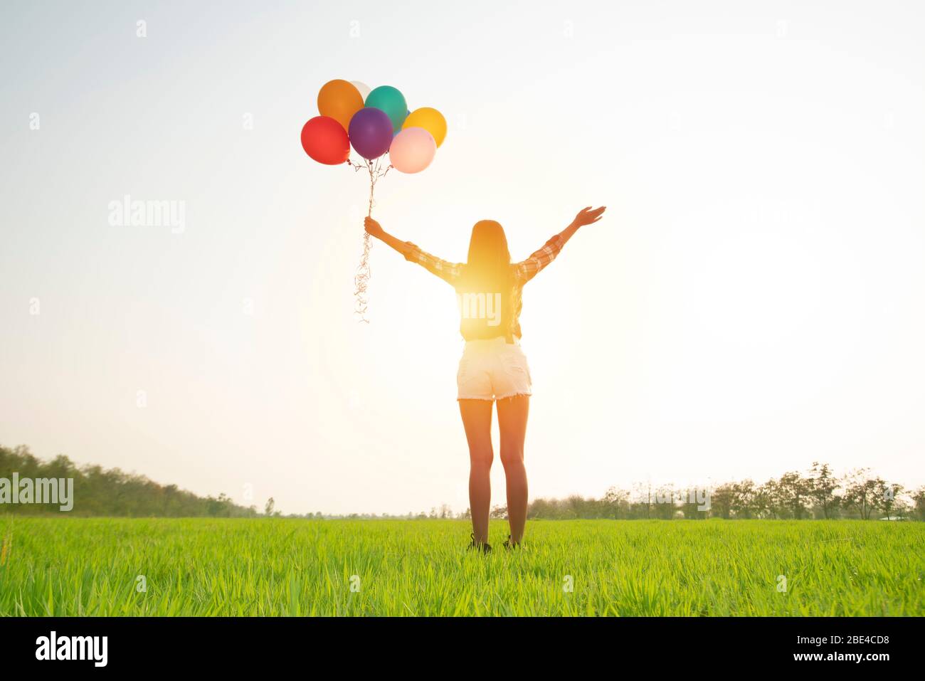 woman with colorful air balloon on green grass in the park with sunlight background Stock Photo