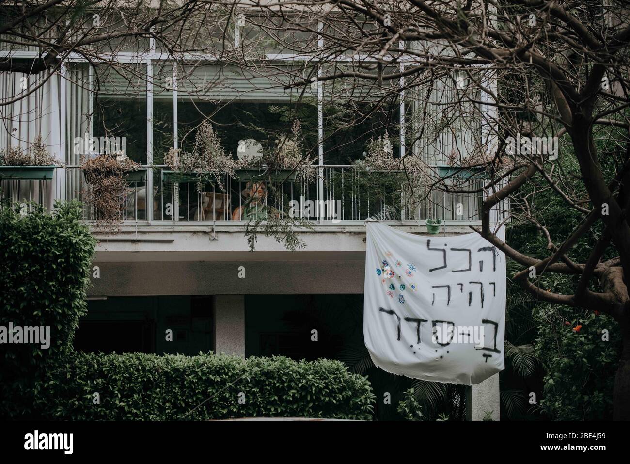 A homemade sign hangs from a balcony stating 'Everything will be OK' in Hebrew as a self support to others during the COVID-19 quarantine. Photographe Stock Photo