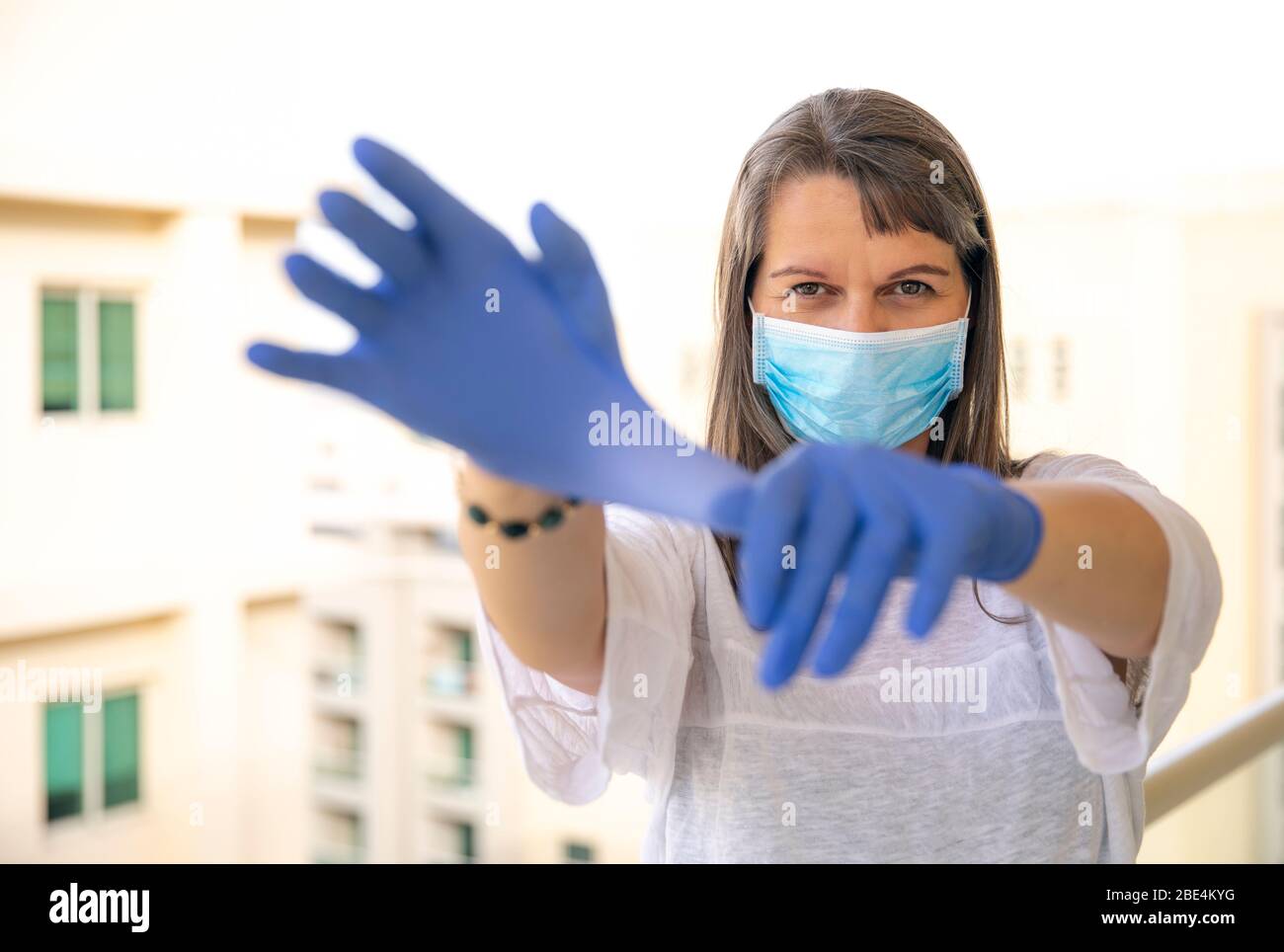 middle aged woman wearing face mask and rubber gloves during a virus outbreak Stock Photo