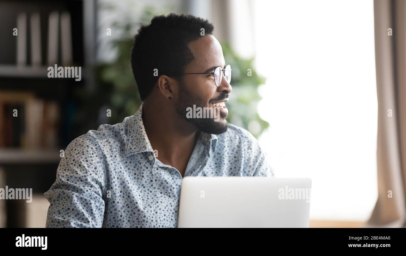 Happy young mixed race man distracted from job, looking aside. Stock Photo