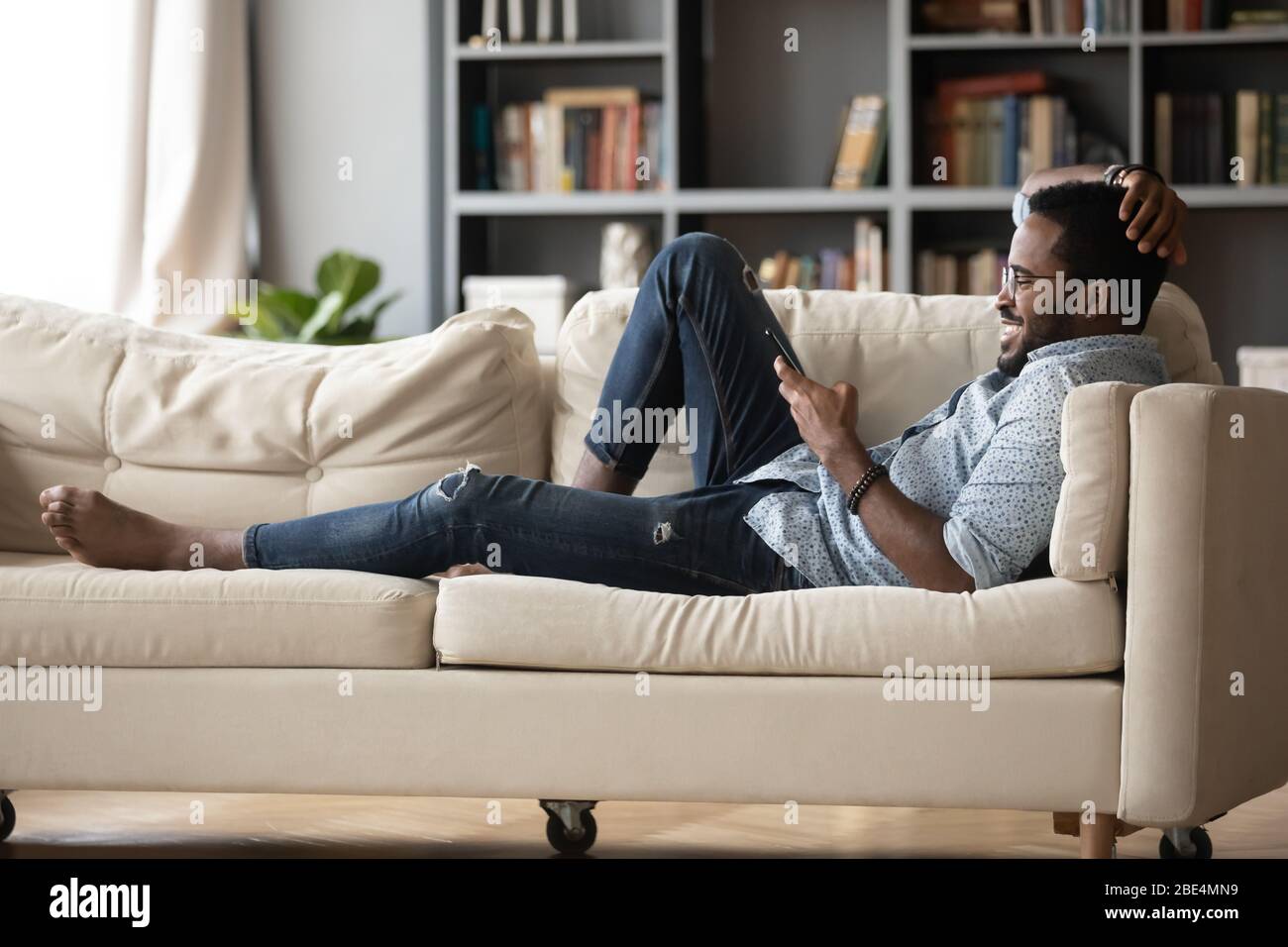 Relaxed young african ethnicity man using mobile phone. Stock Photo