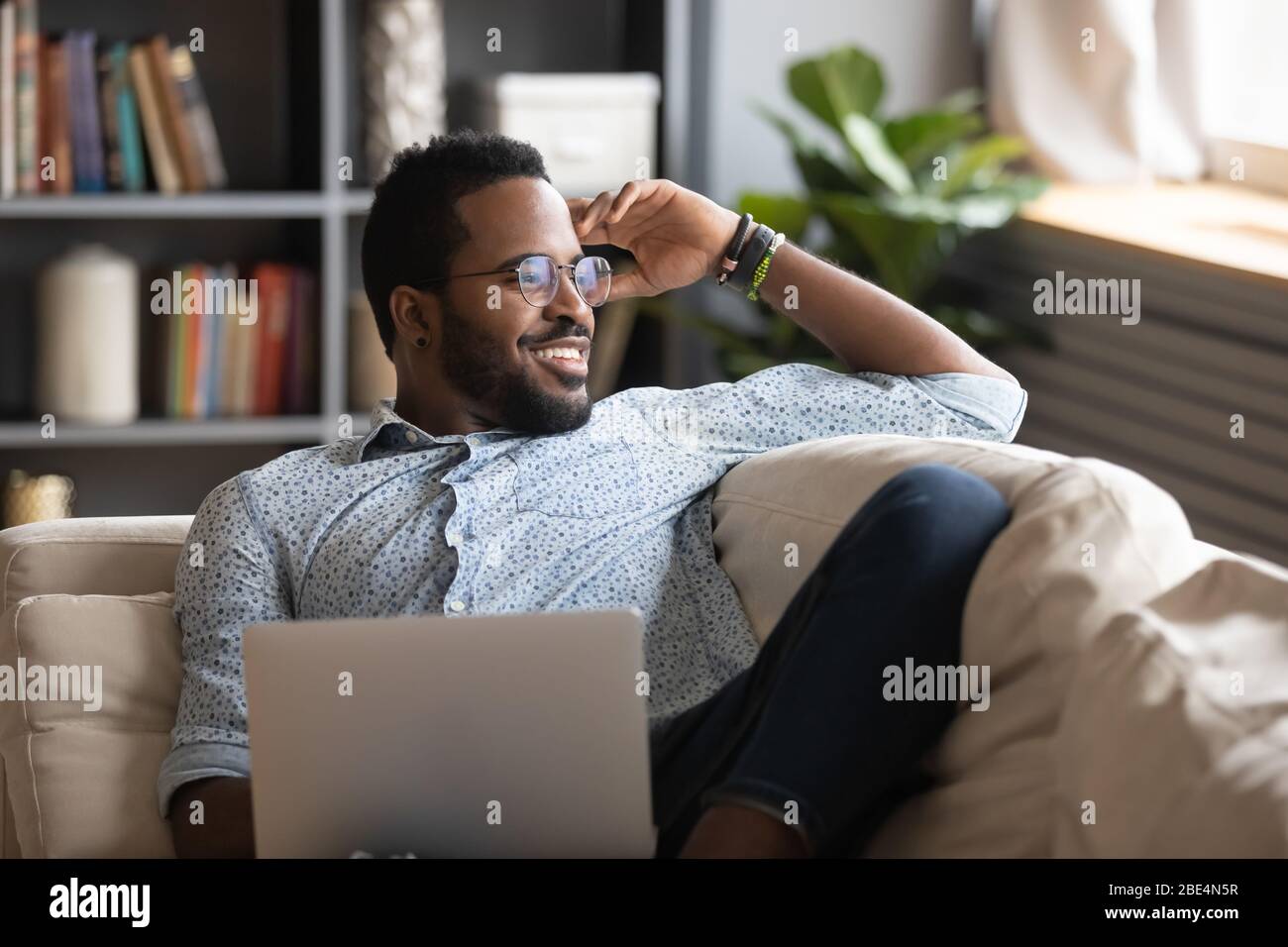 Multiracial freelance guy distracted from job study, looking at window. Stock Photo