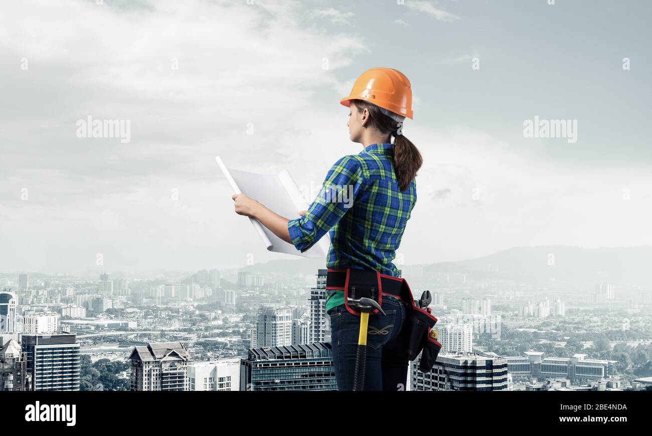 Female engineer in hardhat standing with blueprint Stock Photo - Alamy