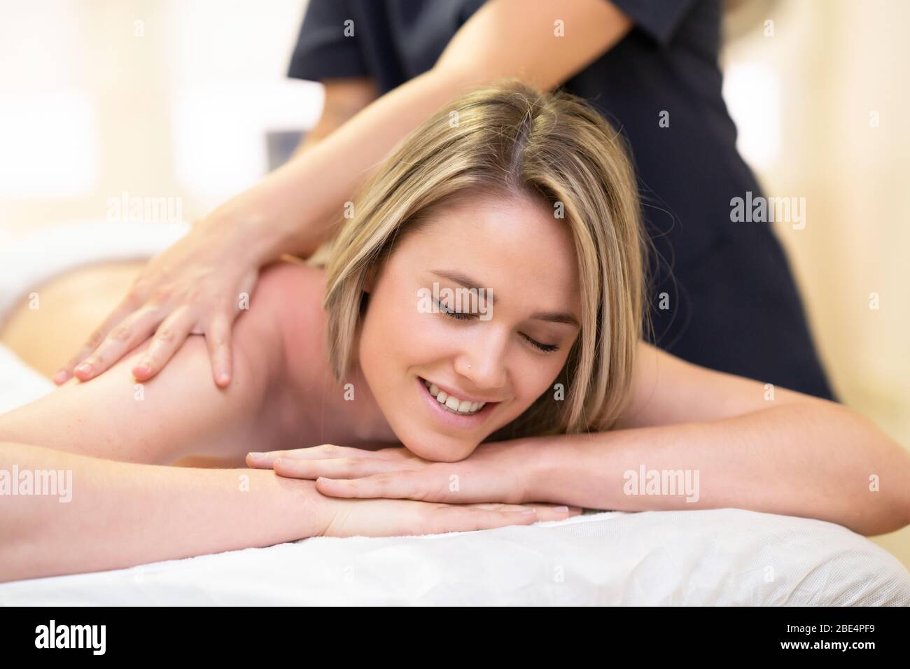 Woman lying on a stretcher receiving a back massage. Stock Photo