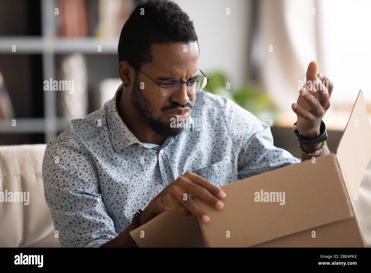Young african american man feeling dissatisfied with received order. Stock Photo