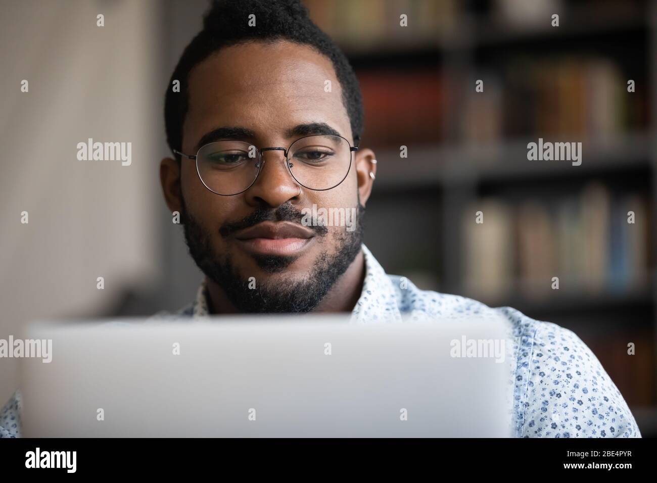 Close up focused young african ethnicity man working on computer. Stock Photo