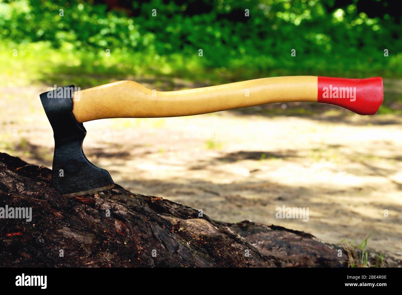 a beautiful-shaped ax sticks out in a tree, with a yellow handle close-up, on a natural background Stock Photo