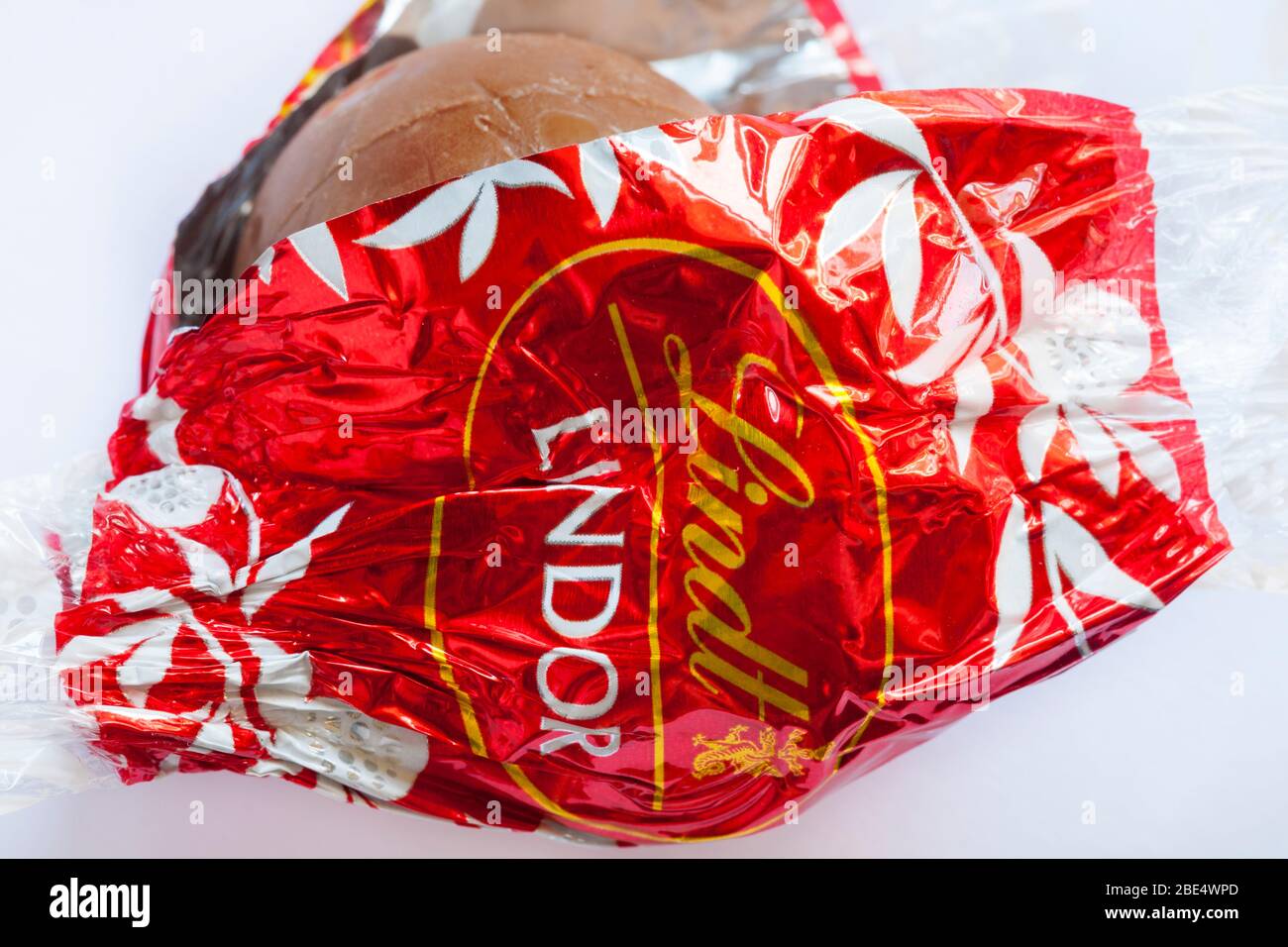 Unwrapping Lindt Lindor chocolate wrapper to show contents set on white