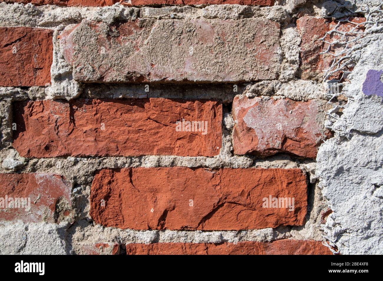 red brick wall detail with damaged plaster Stock Photo