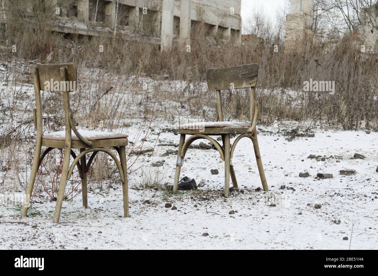 Hopelessness. Sadness. Yearning. Loneliness. Two old chairs stand in an empty field Stock Photo