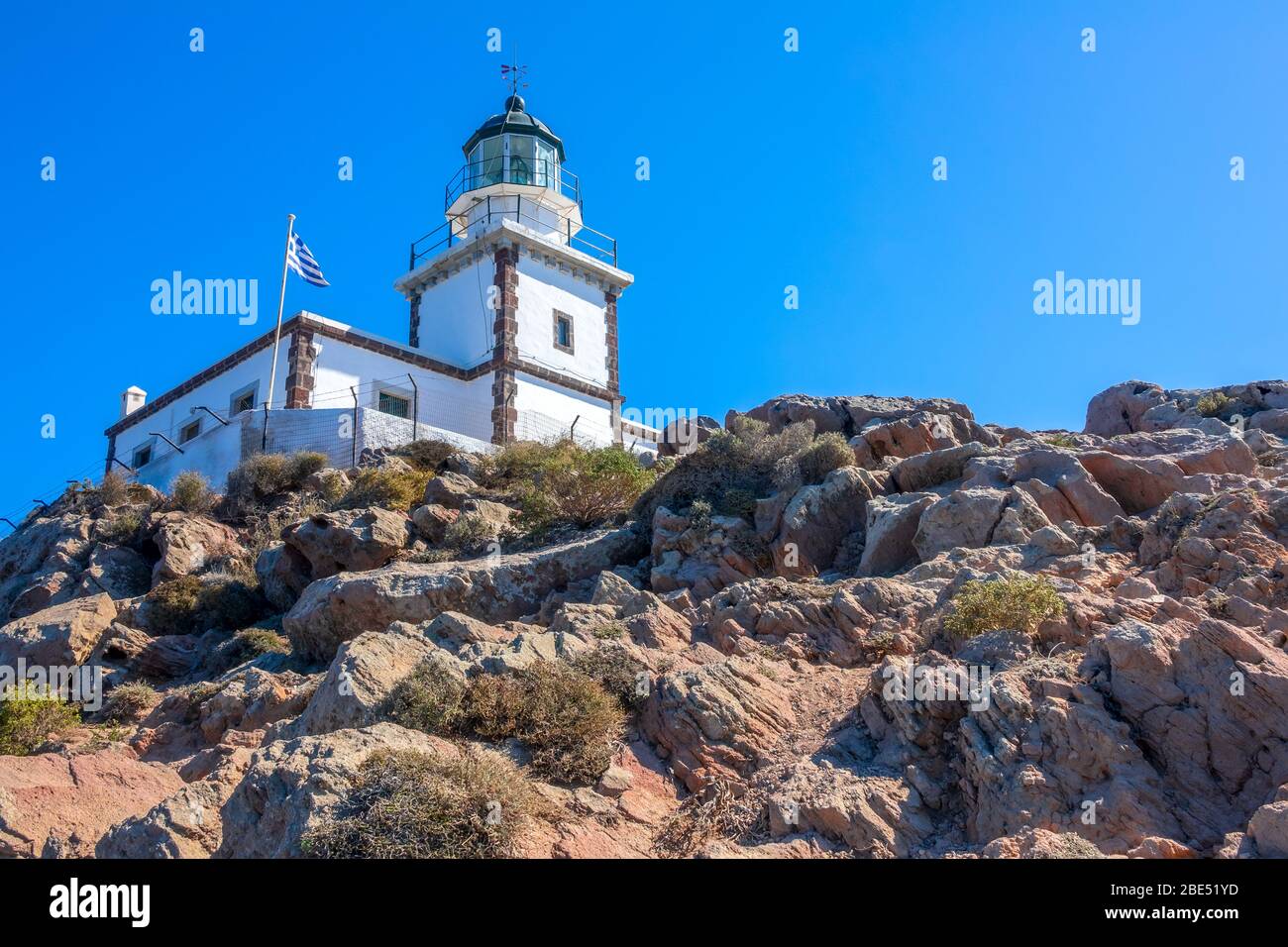 Greece. Rocky mountain on a sunny day. Lighthouse building and national flag against the blue sky Stock Photo