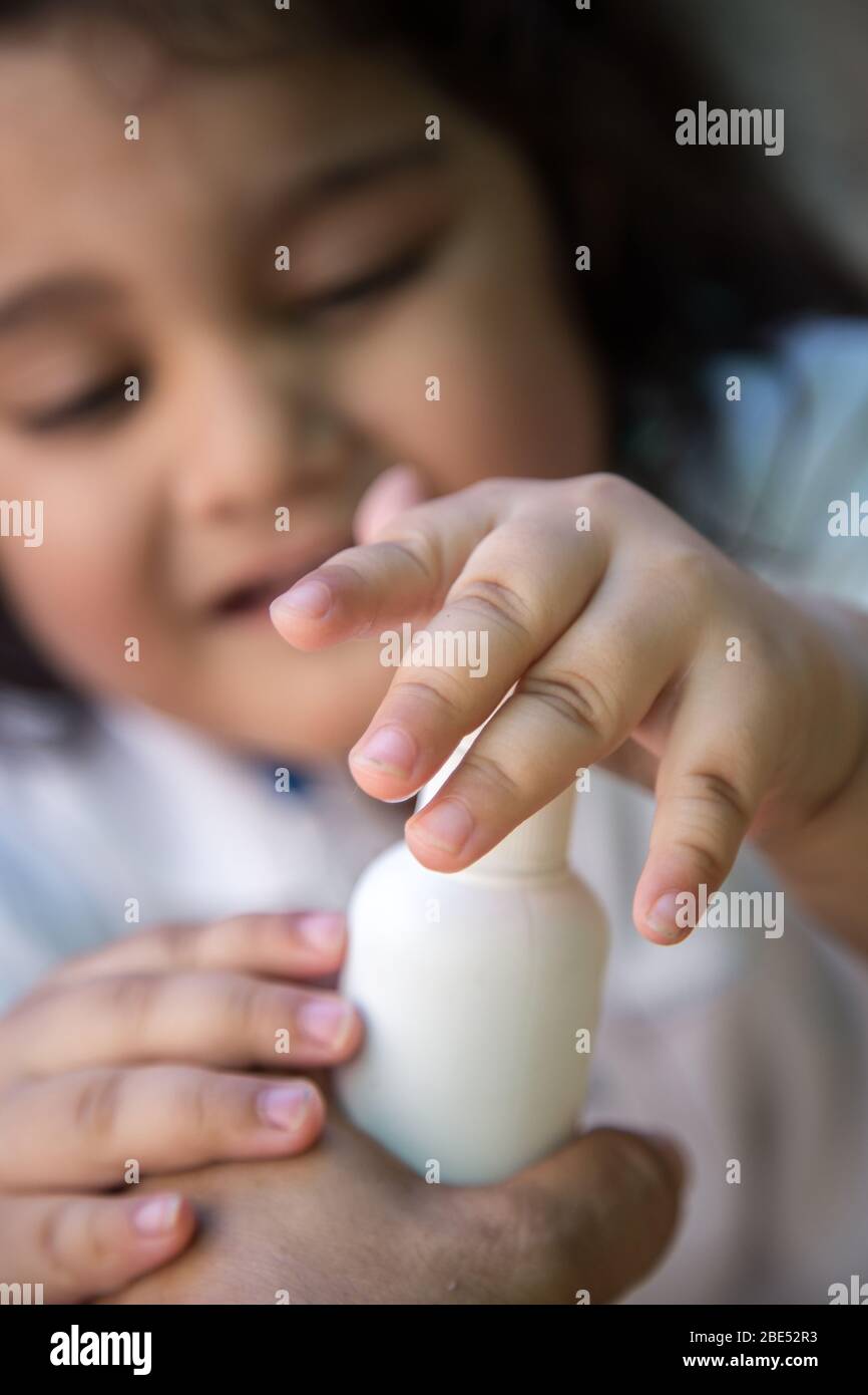 Close up of kid hand holding bottle with antiseptic cleaning gel. Kids