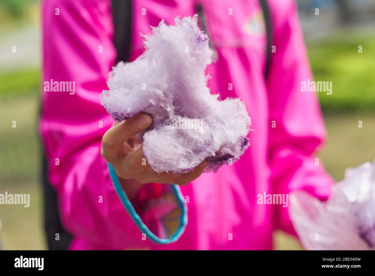 Girl child eating cotton candy floss, closeup sweet pink cloud. Stock Photo