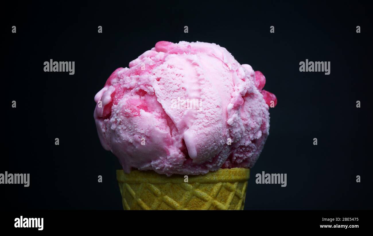 Strawberry ice cream scoop in waffle cone on black background, Front view Food concept. Stock Photo