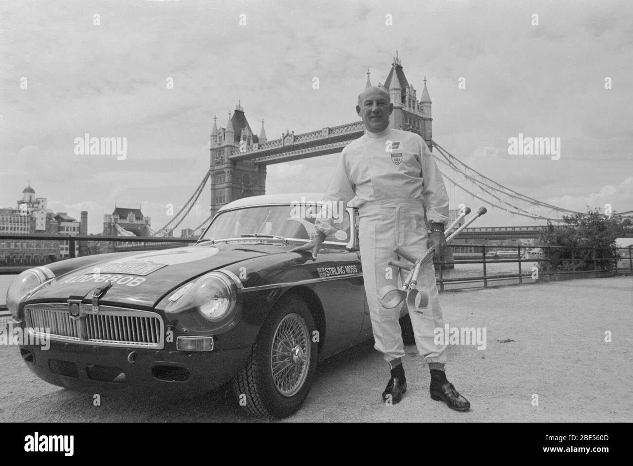 File photo dated 07-06-1990 of Motor racing ace Stirling Moss, 60, holding crutches he has been using since breaking a leg in a scooter-riding accident, smiles as he reveals he has been giving the all-clear to drive in the Pirelli Classic Marathon. He is stood next to an MGB, the car he will drive in the race. Stock Photo