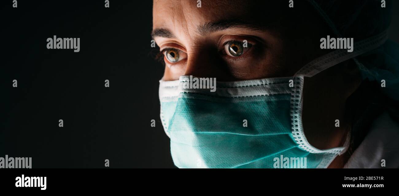 Woman Doctor wearing protection face mask and against coronavirus on black background. Banner panorama medical staff preventive gear. Isolate doctor C Stock Photo