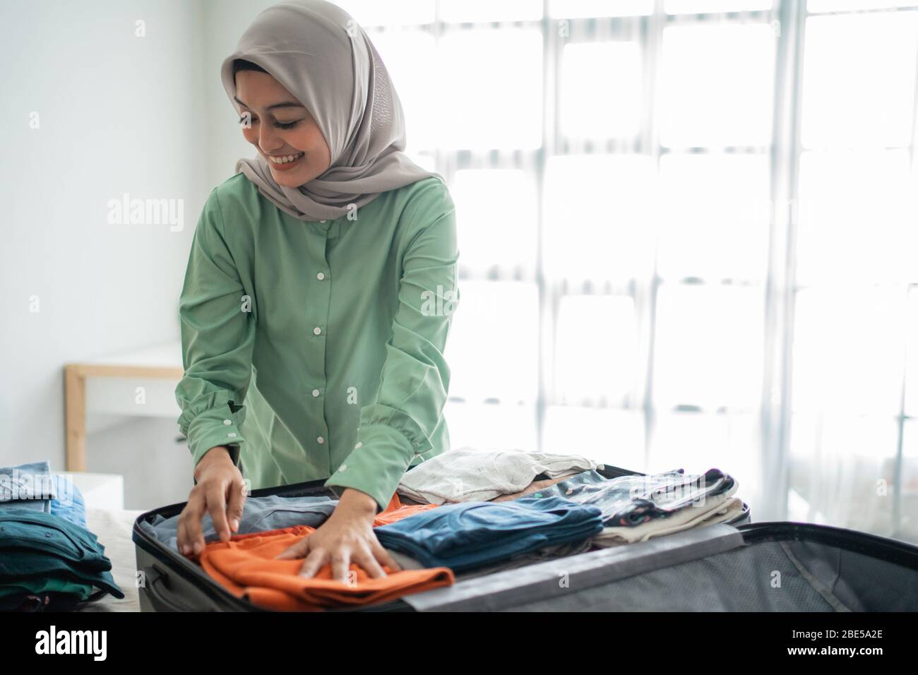 Packing Hijab Muslim women wearing hijabs prepare clothes to be put in a suitcase ...