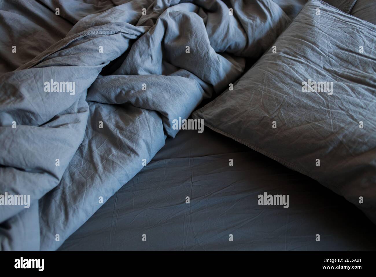 A gray cotton sheet and blankets with pillows on the bed Stock Photo