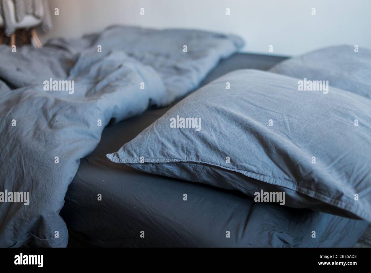Closeup of gray pillows and blankets with a sheet on the bed Stock Photo