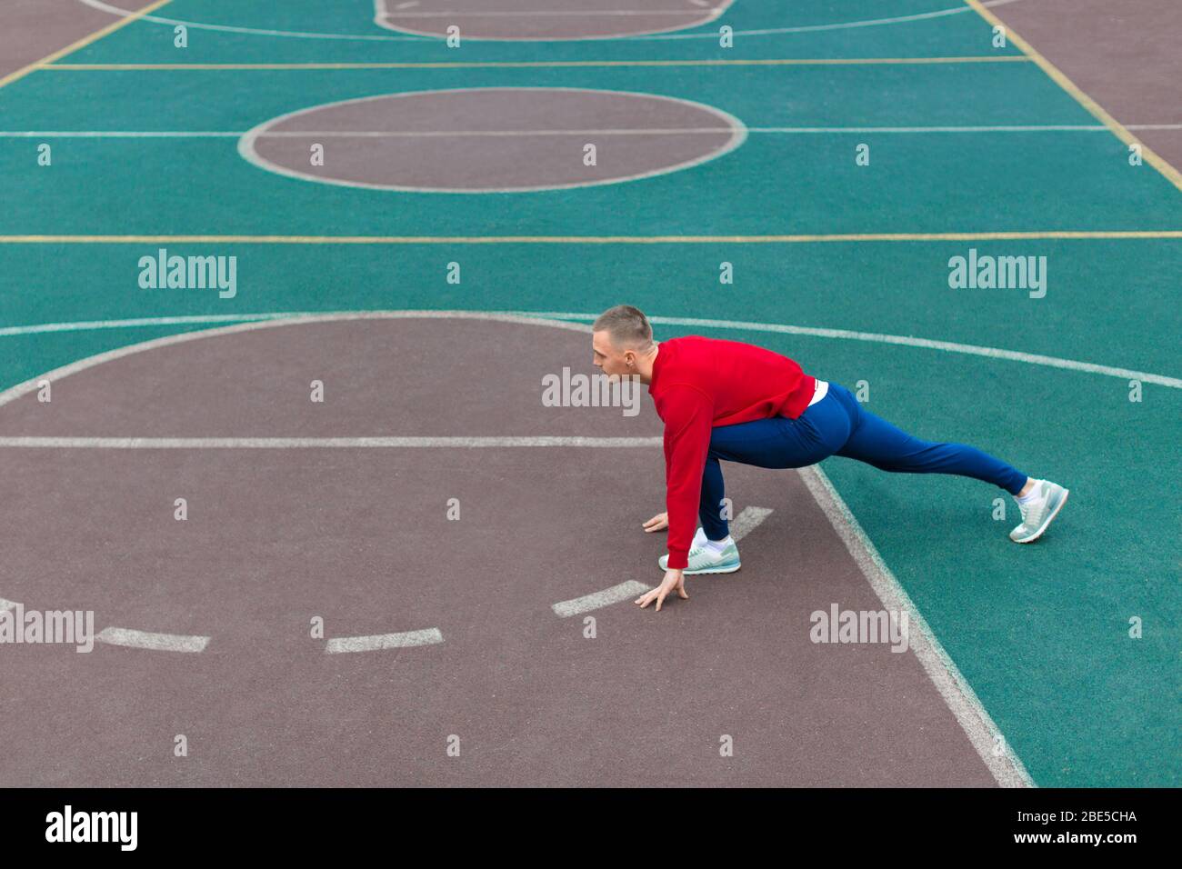 Photo of a man man flexes his leg muscles on the sports ground before running. Healthy lifestyle concept. Stock Photo