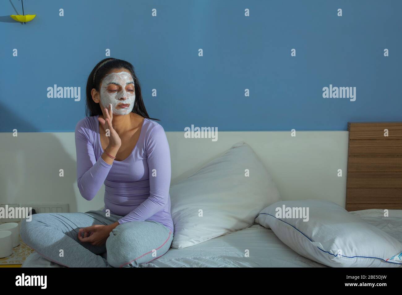 Young woman applying face-pack on her face. Stock Photo