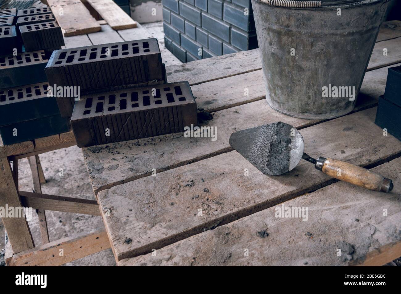 A mason tool by a stern plan in the workplace. Trowel for bricklaying. Construction mason cement